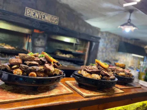 Braseros listos sobre la barra frente a la parrilla a leña