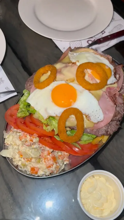 Chivito al plato con huevo frito, jamón, aros de cebolla y ensalada