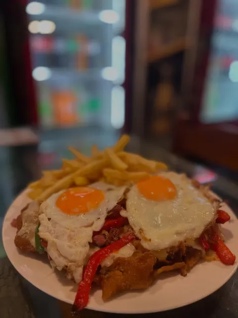 Milanesa criolla con huevos fritos, morrón asado y papas fritas